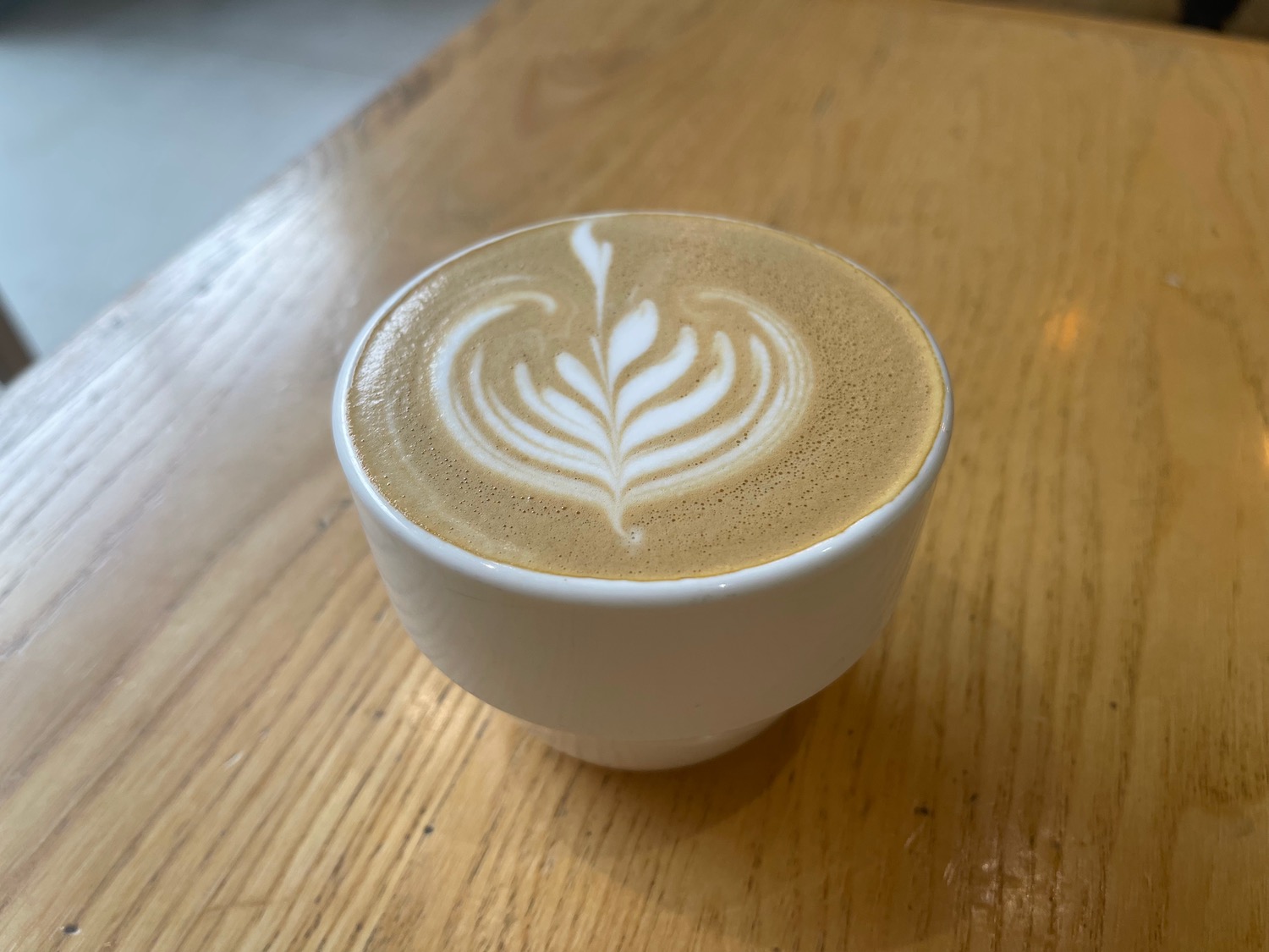 a cup of coffee with a leaf design in the foam