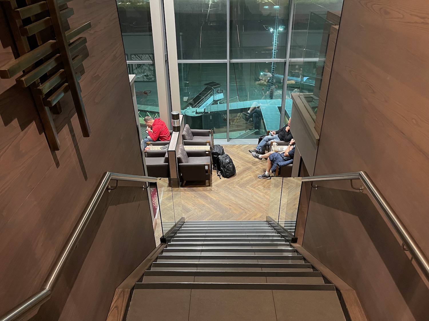 a staircase with glass walls and people sitting on it