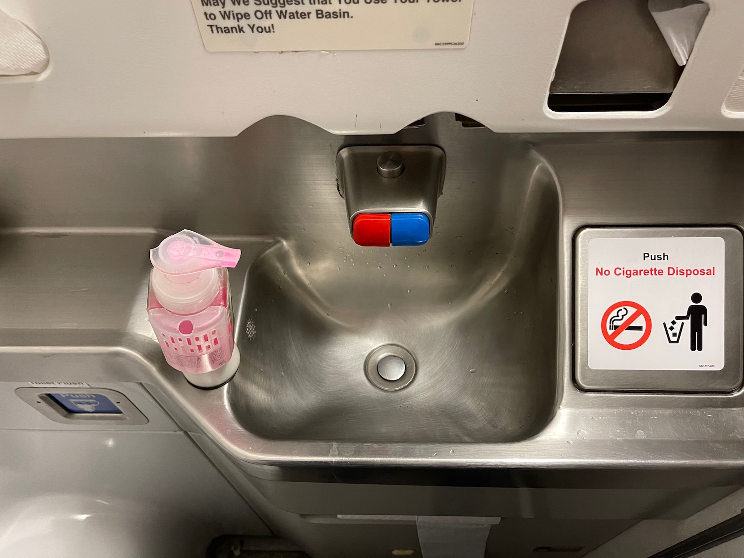 a sink with a bottle of liquid and a no smoking sign