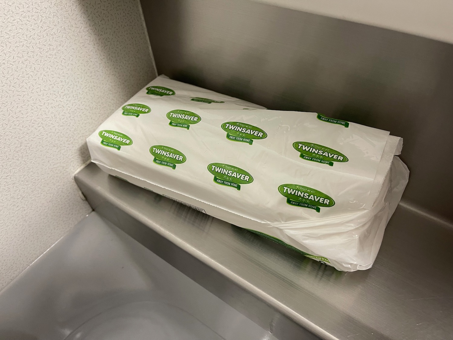 a stack of white plastic bags with green labels on a silver shelf