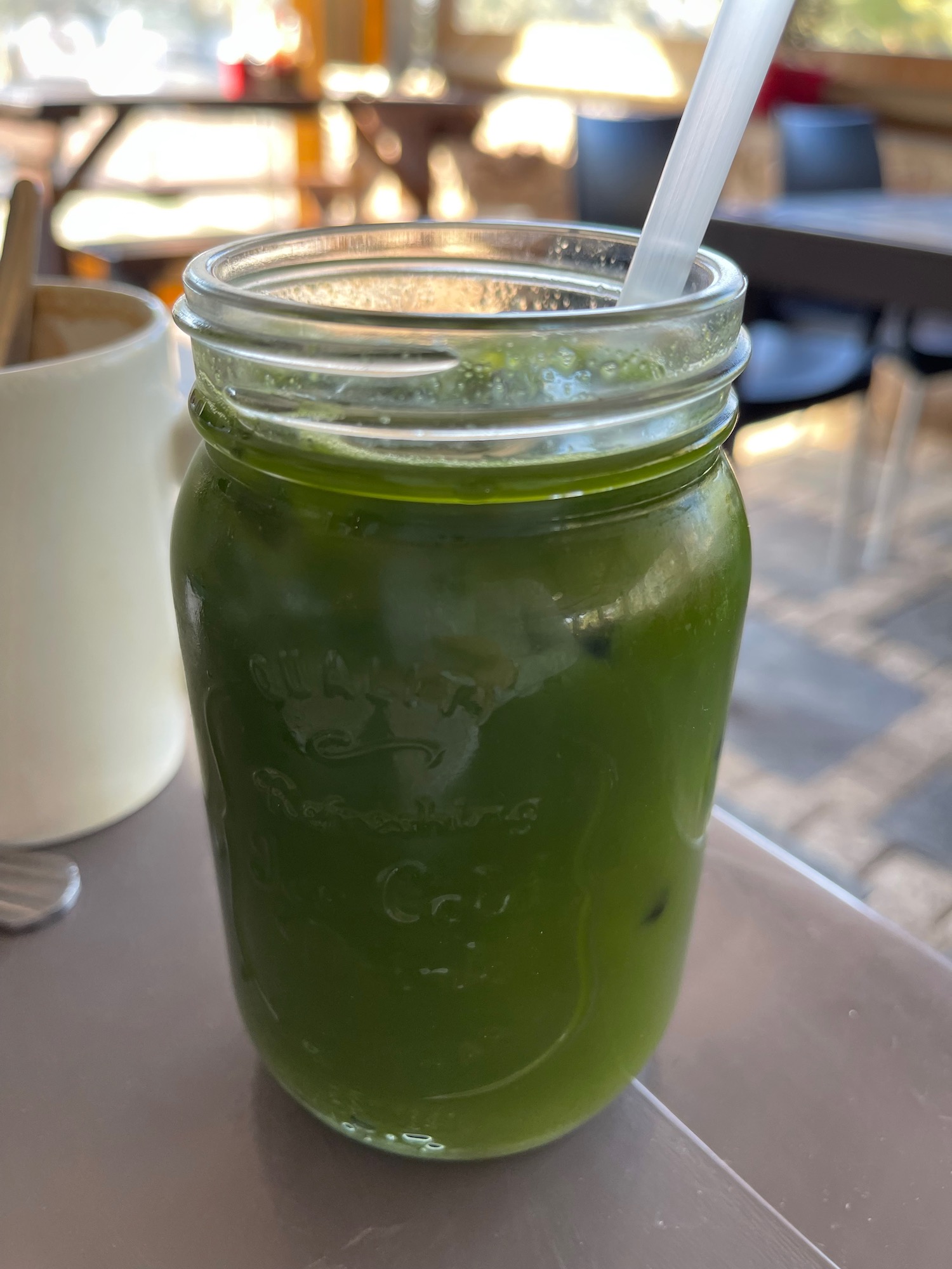 a green drink in a glass jar with a straw