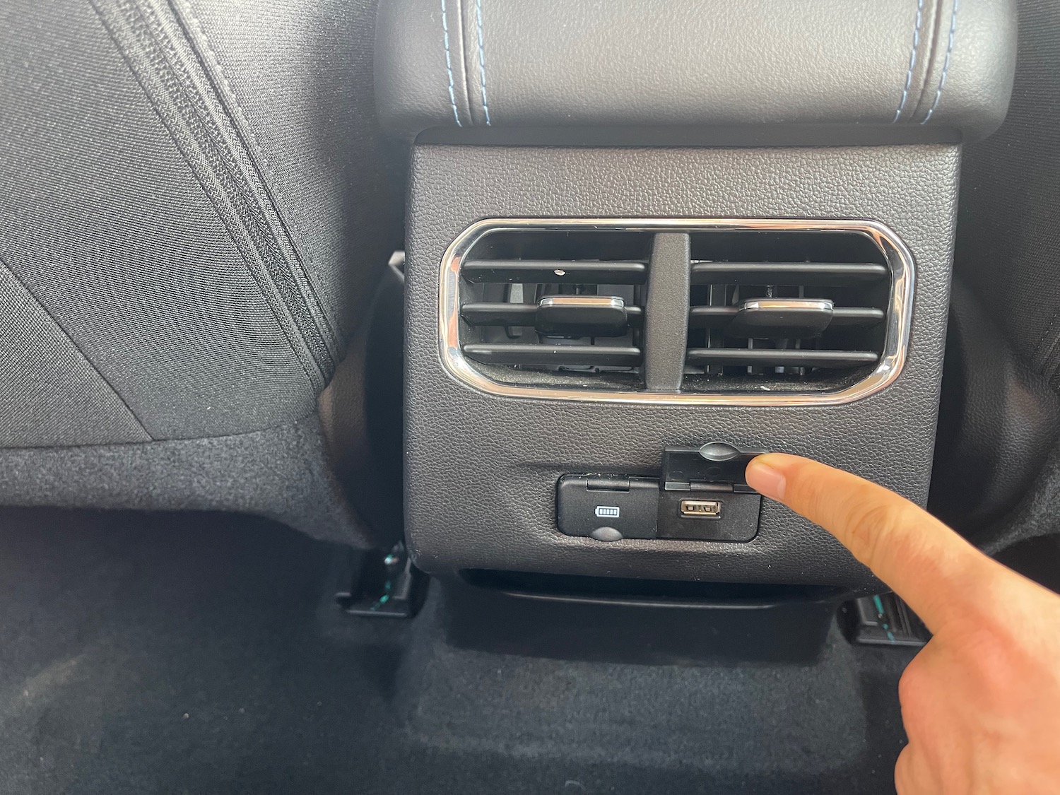 a finger pressing a button on a car vent