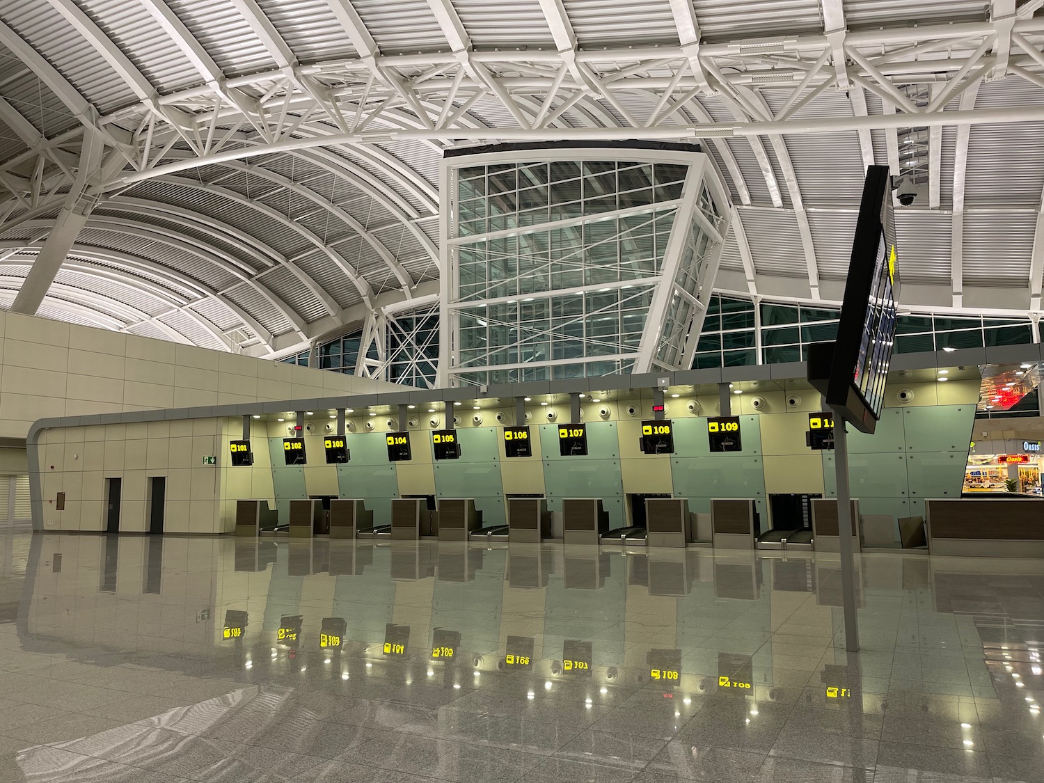 a large airport terminal with a row of monitors