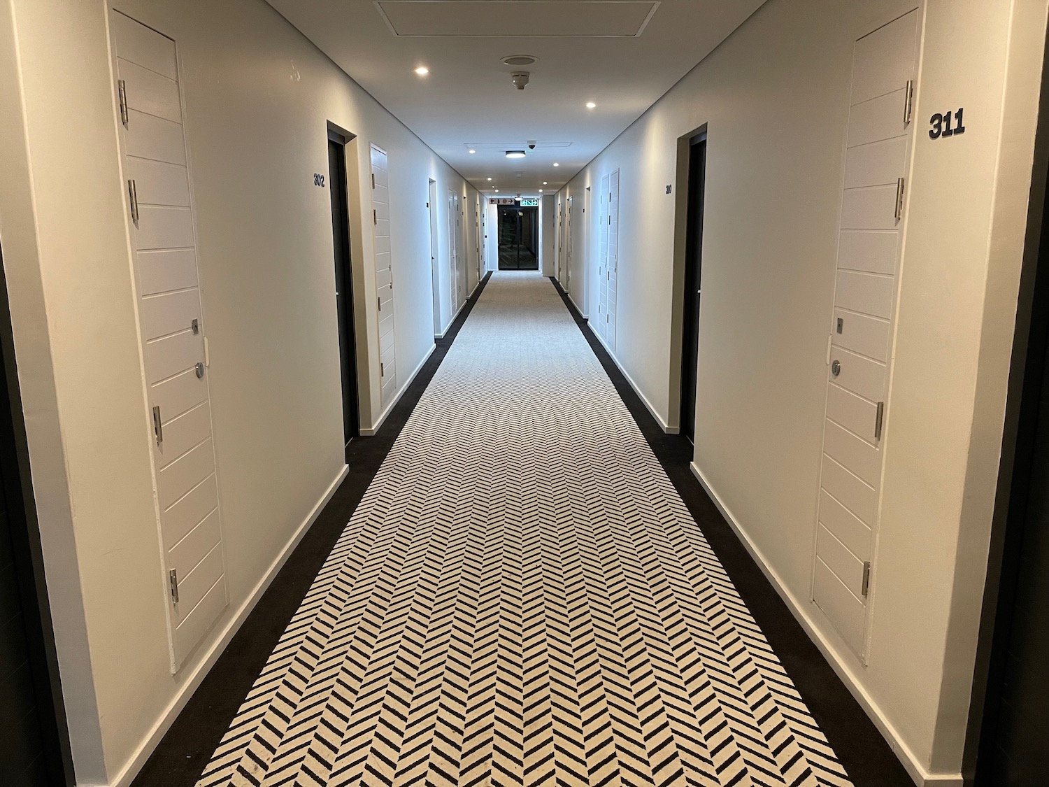 a hallway with white walls and black and white carpet