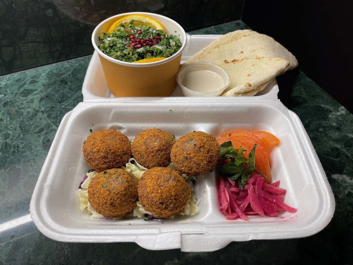 a styrofoam container with food and a bowl of salad