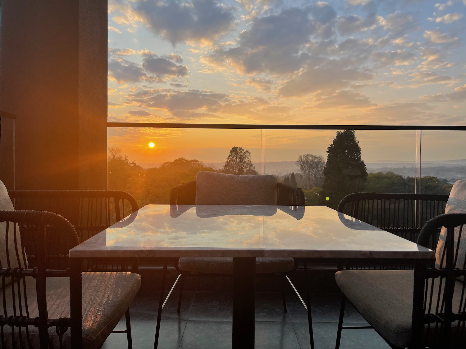 a table and chairs on a patio with a sunset in the background