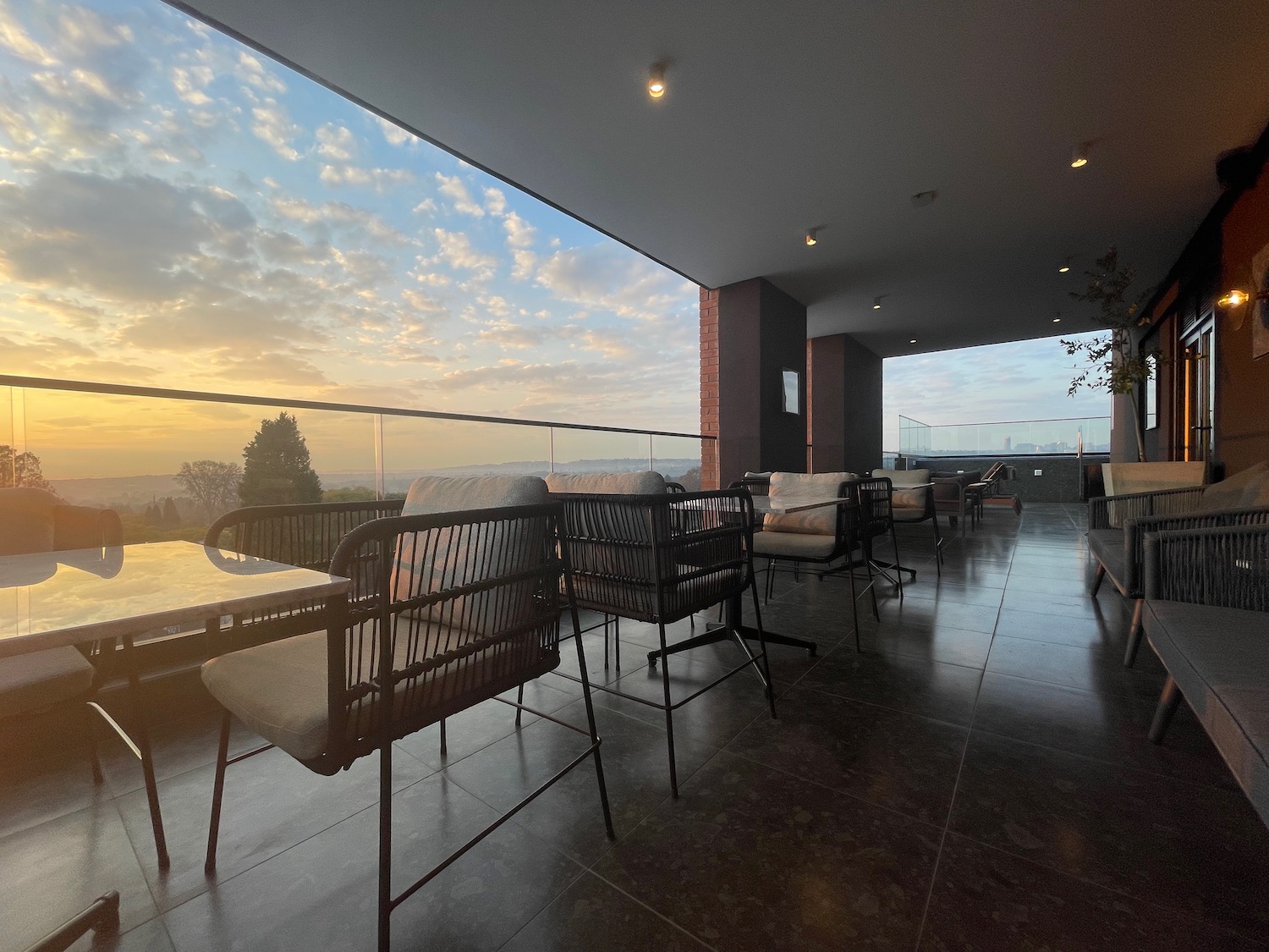 a patio with chairs and a view of the sunset