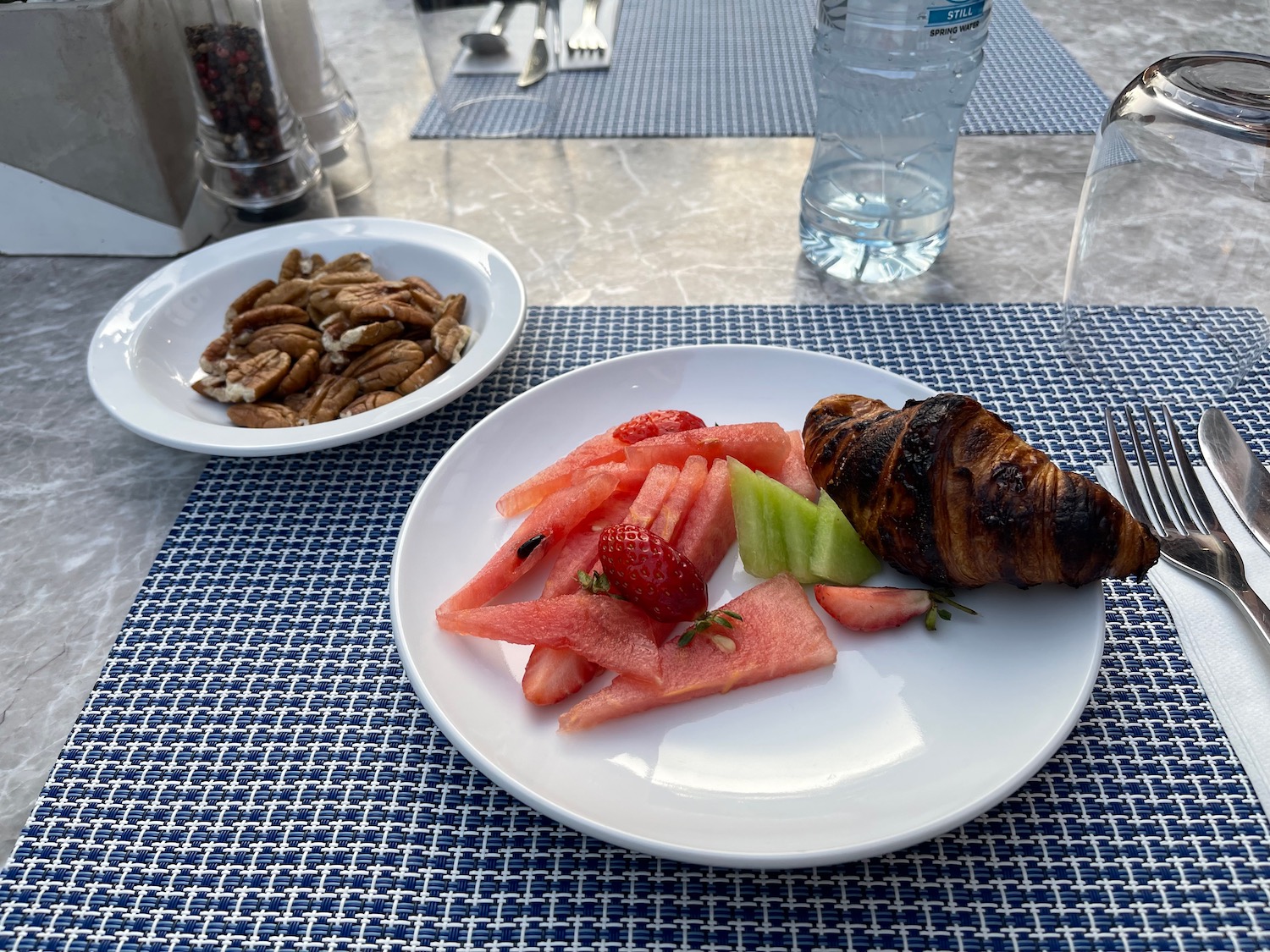 a plate of fruit and water bottle on a table