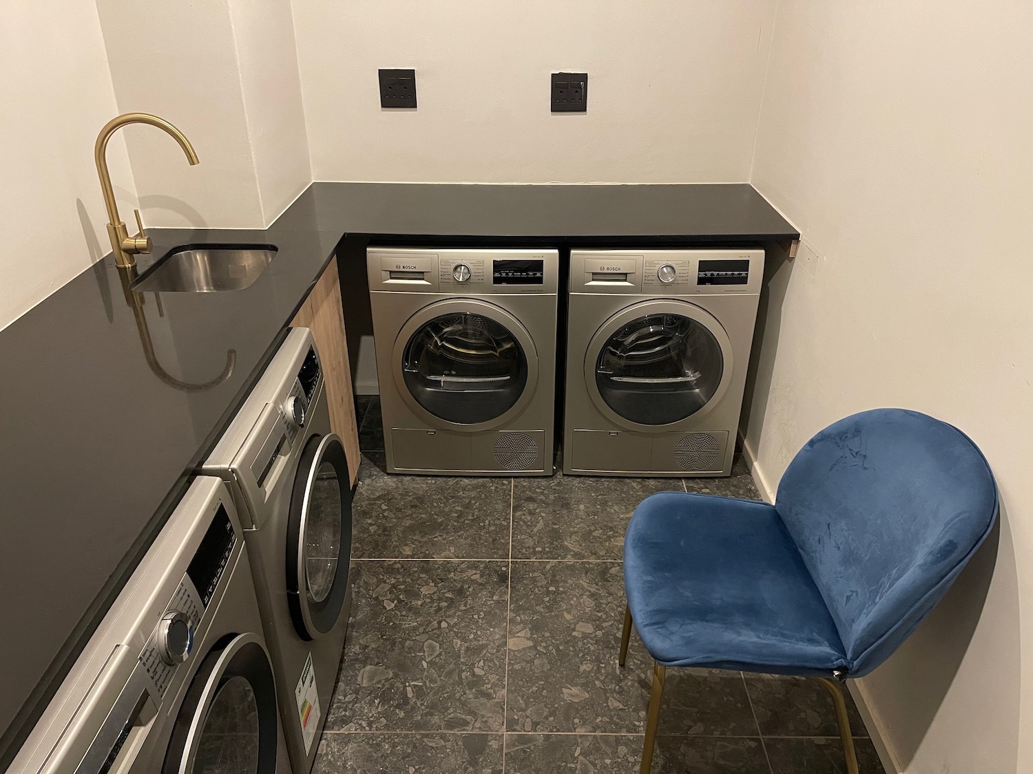 a laundry room with a blue chair and washer and dryer