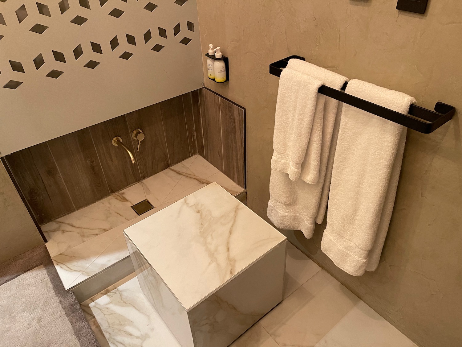 a bathroom with a marble shower and white towels