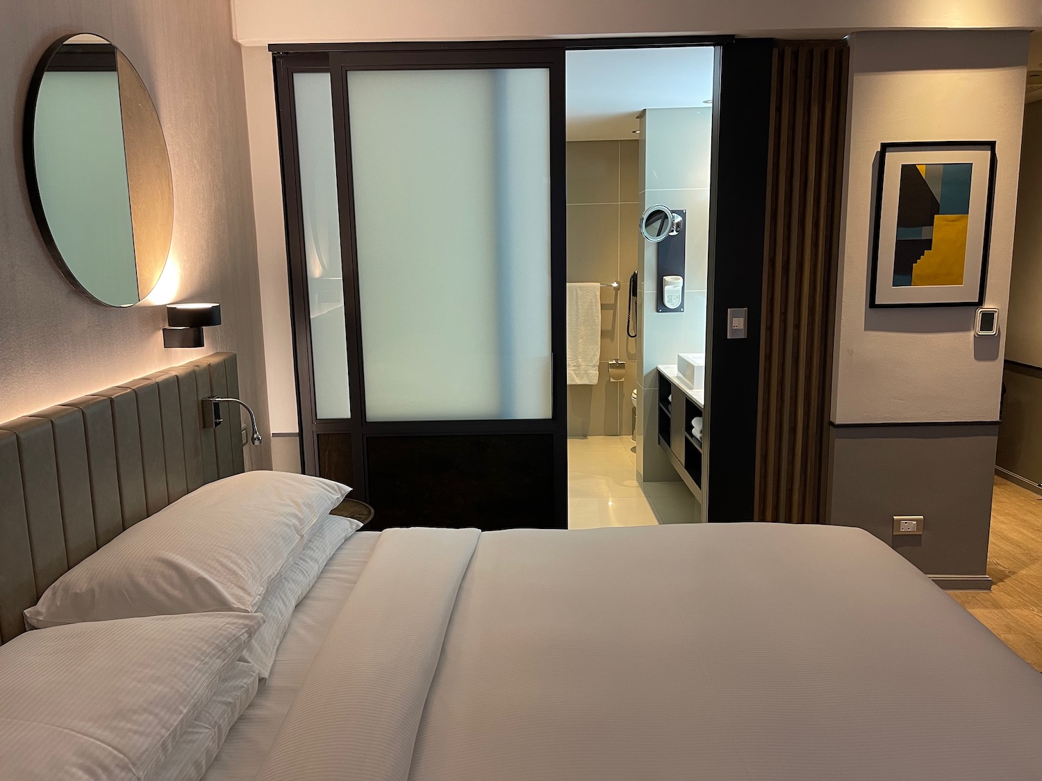 a bed with white sheets and a mirror in a room