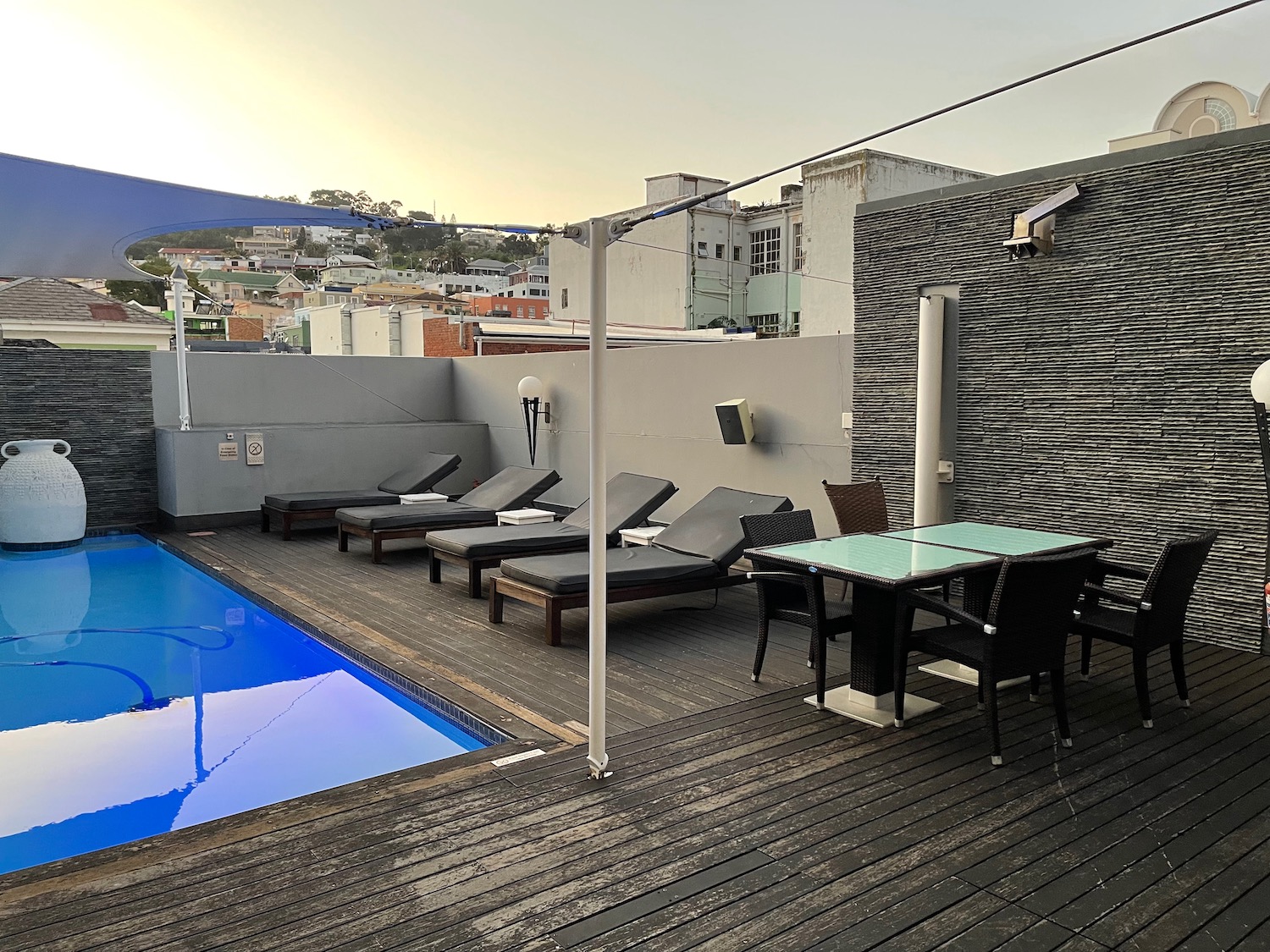 a deck with chairs and a pool on a rooftop