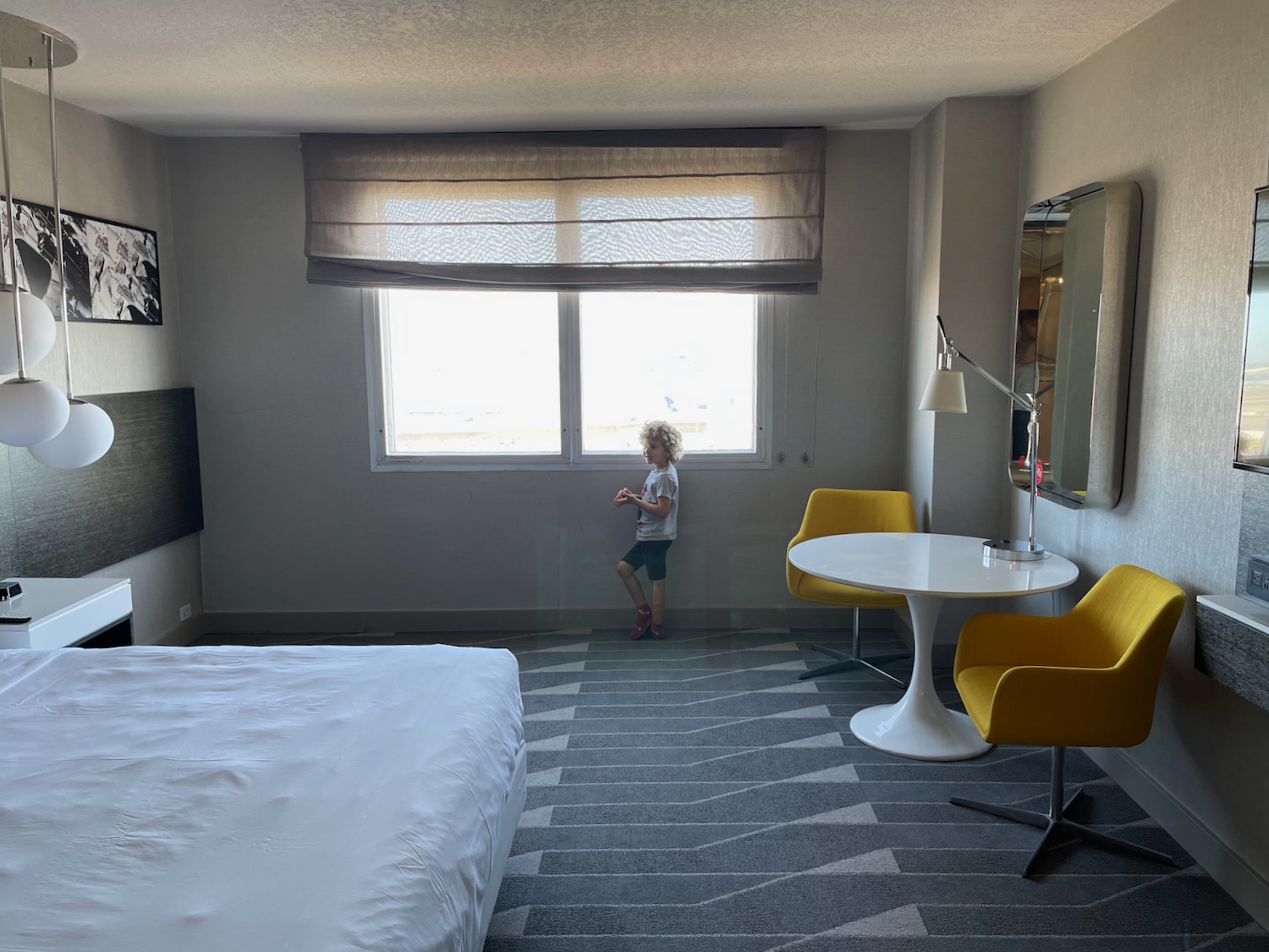 a child standing in a room with a bed and a table