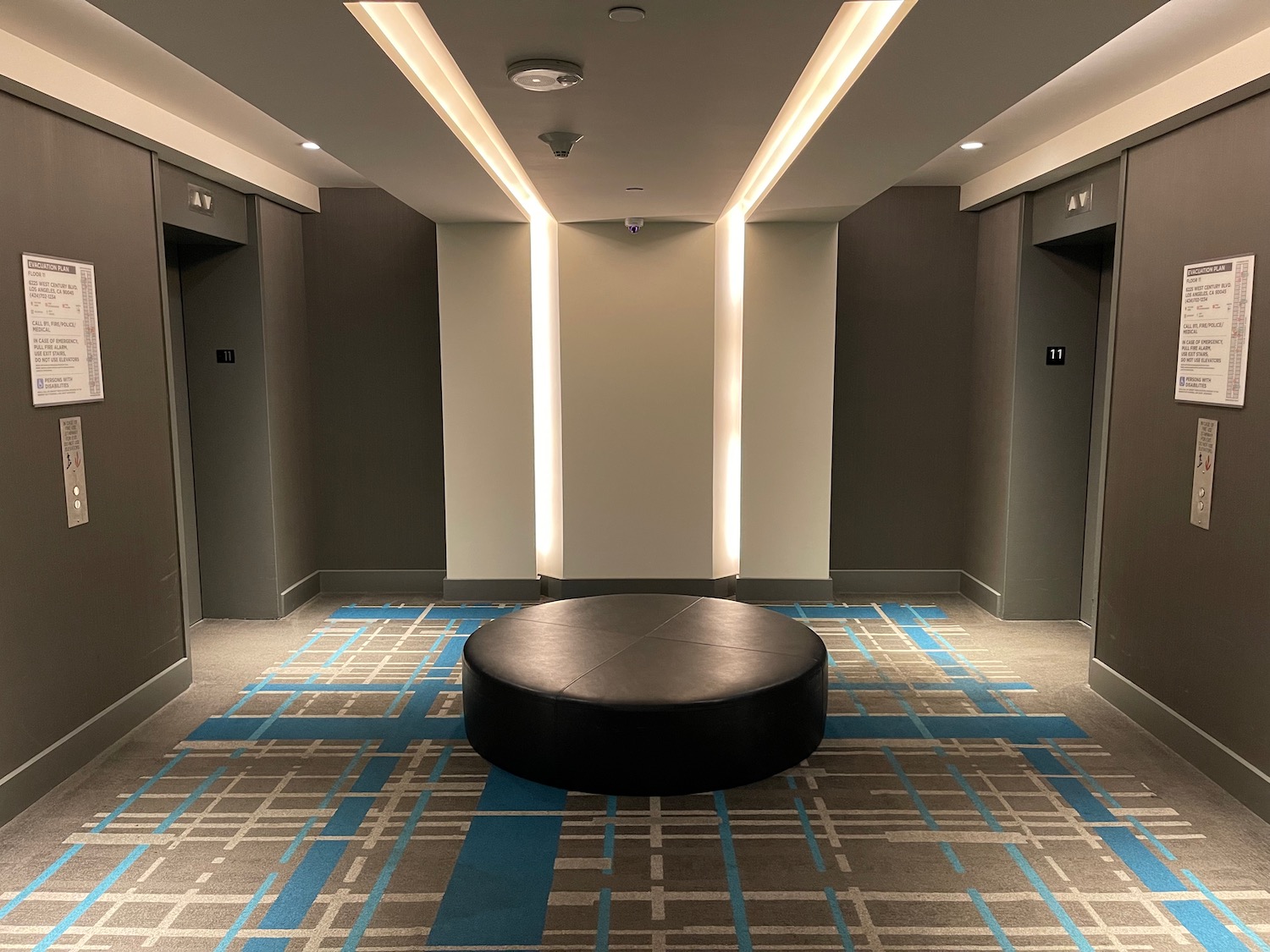 a round black seat in a room with blue and white patterned carpet