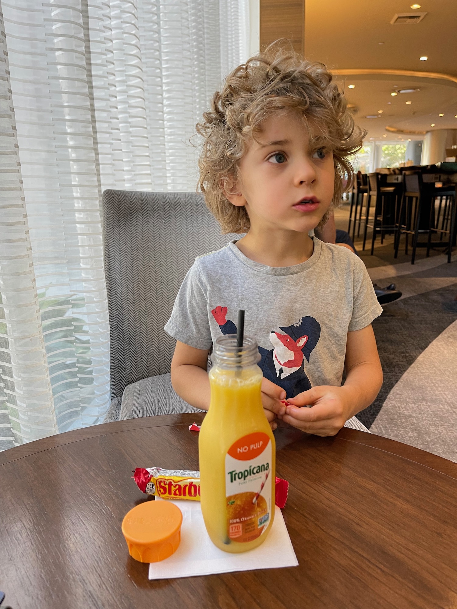 a child sitting at a table with a drink and a straw