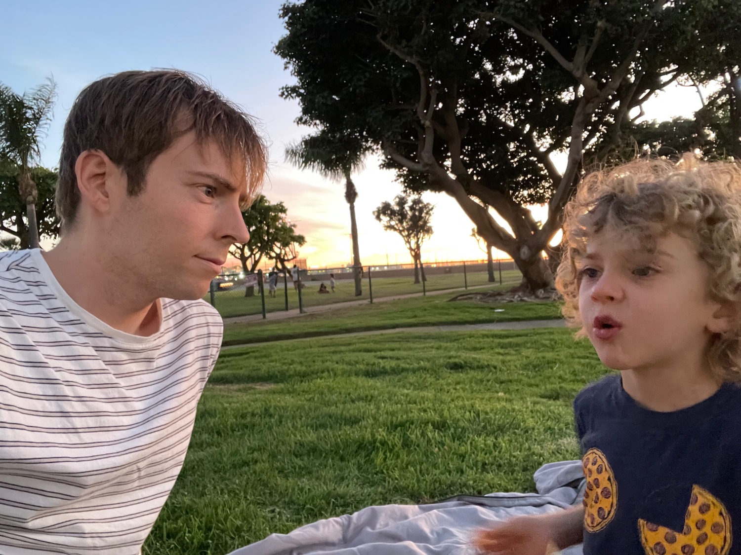 a man and child sitting on grass in a park