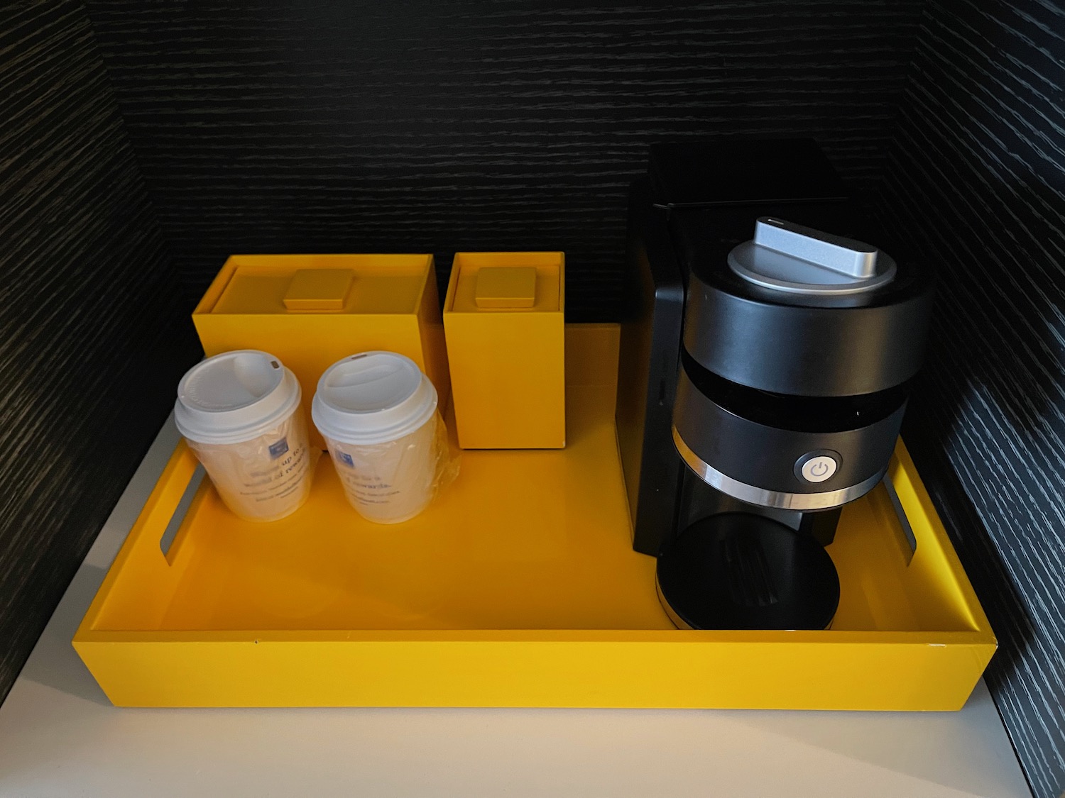 a yellow tray with coffee maker and two cups