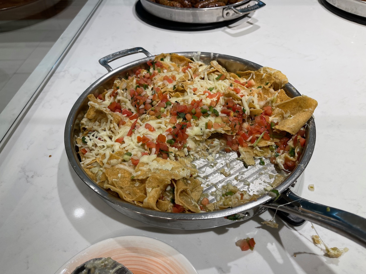 a pan of nachos with cheese and tomatoes