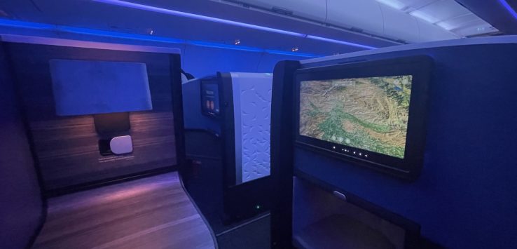 a desk and computer screens in an airplane