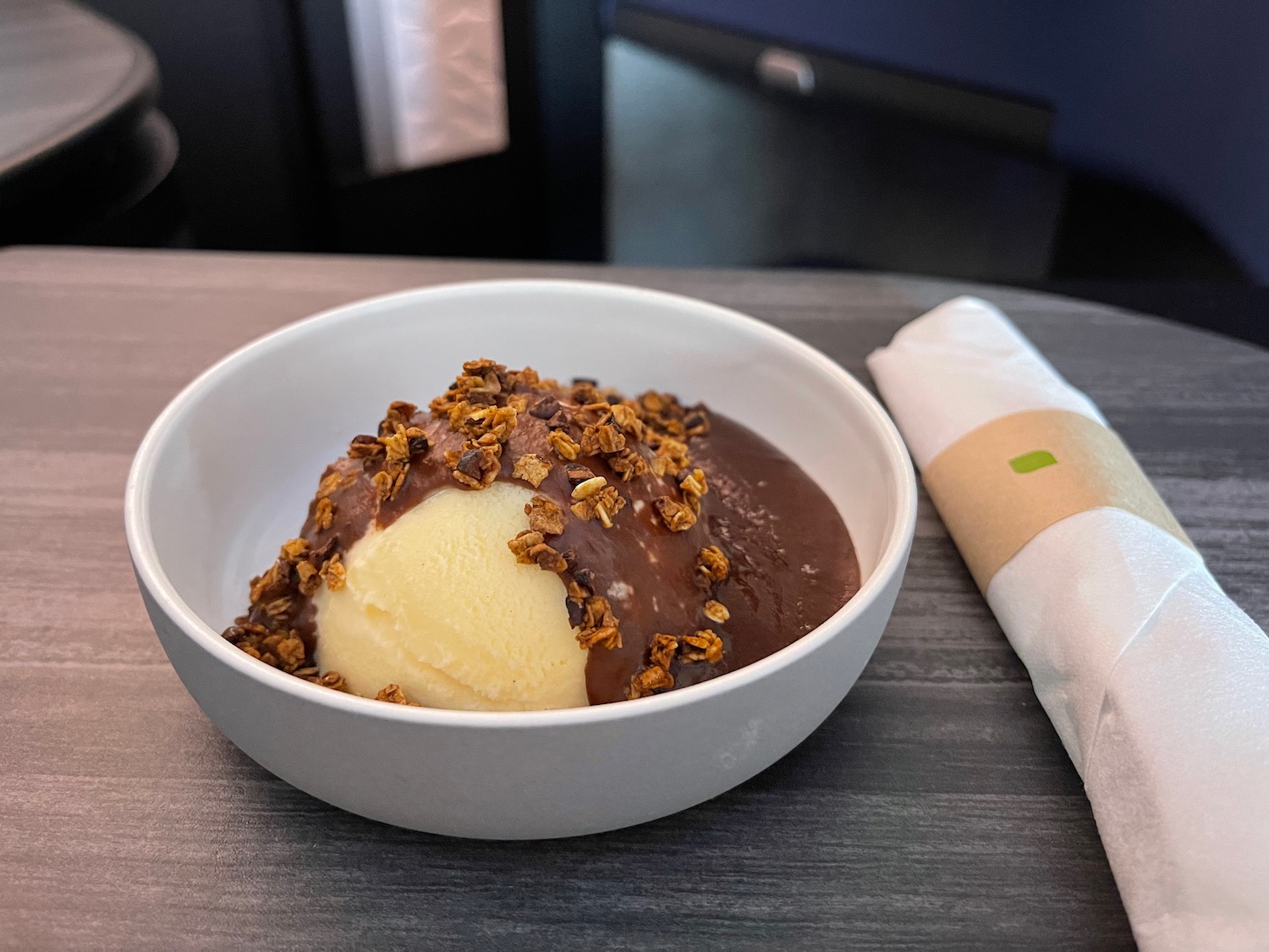 a bowl of ice cream with chocolate topping and a napkin