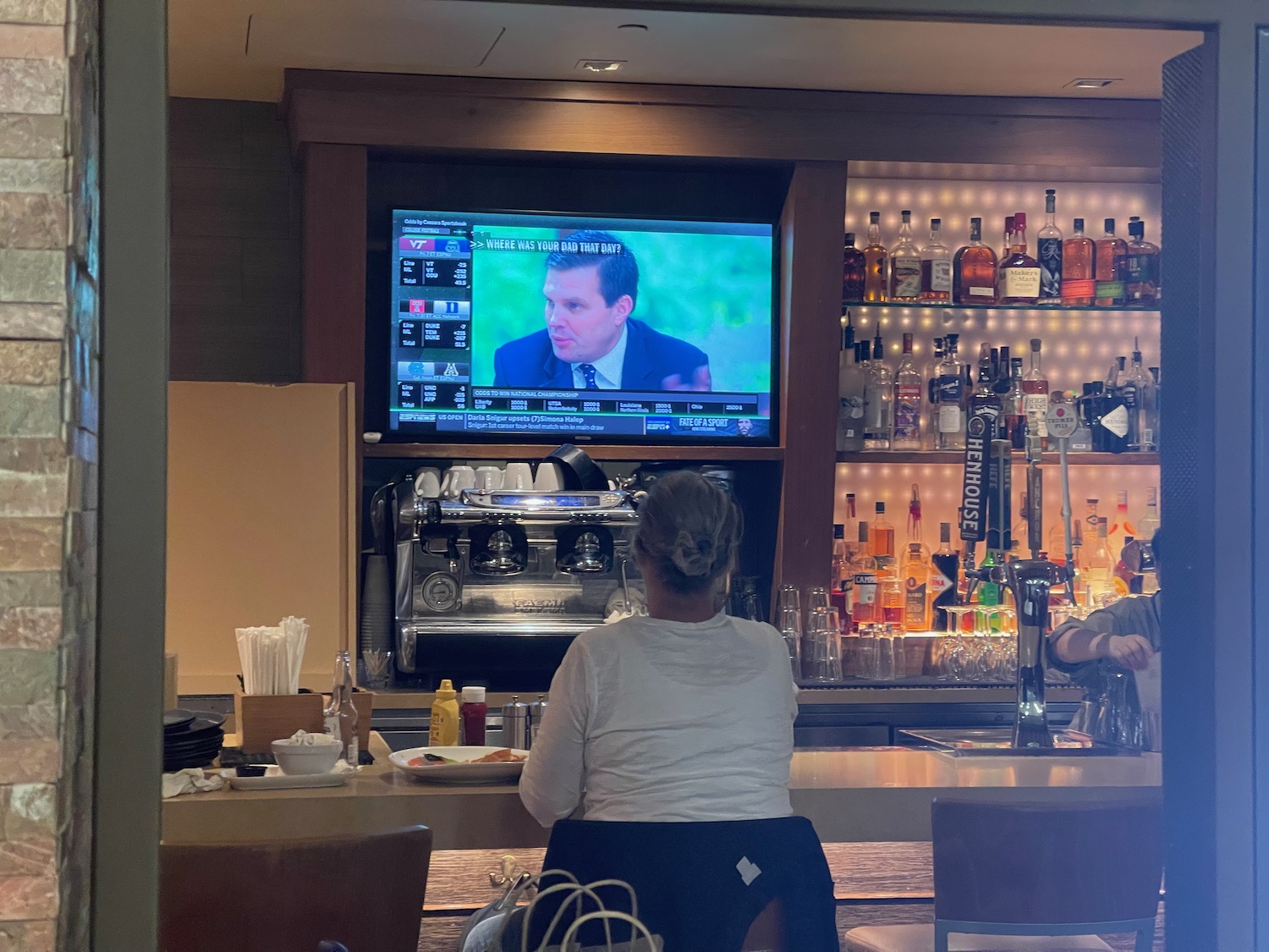 a woman sitting at a bar with a television on the wall