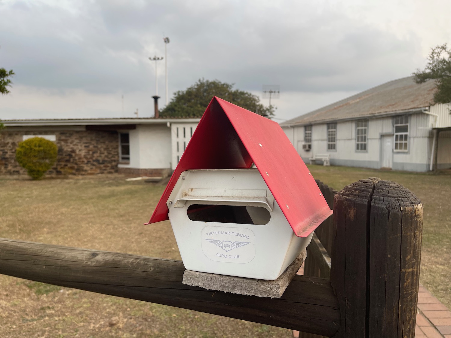 a white and red bird house on a fence