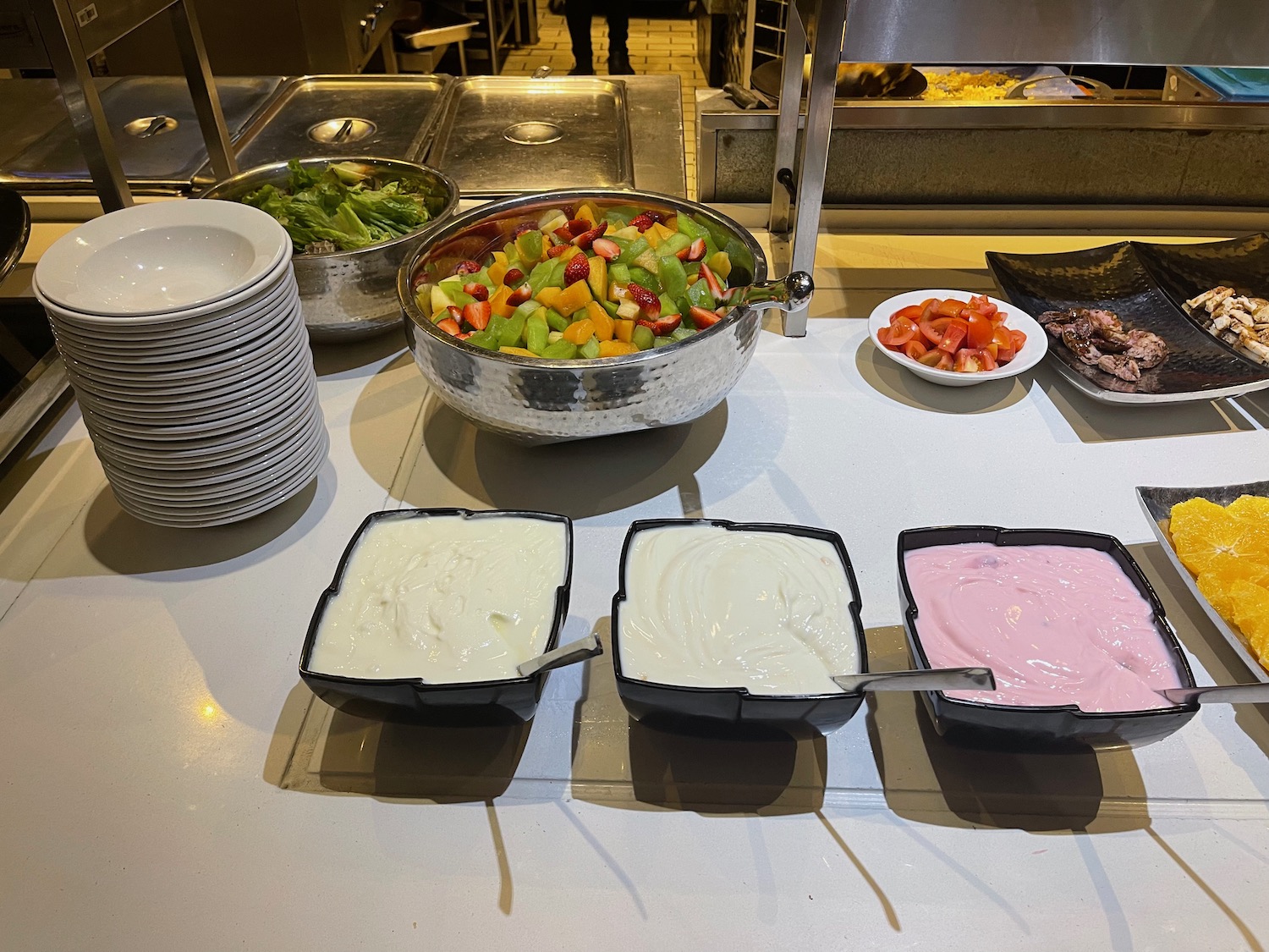 a buffet table with bowls of fruit and yogurt