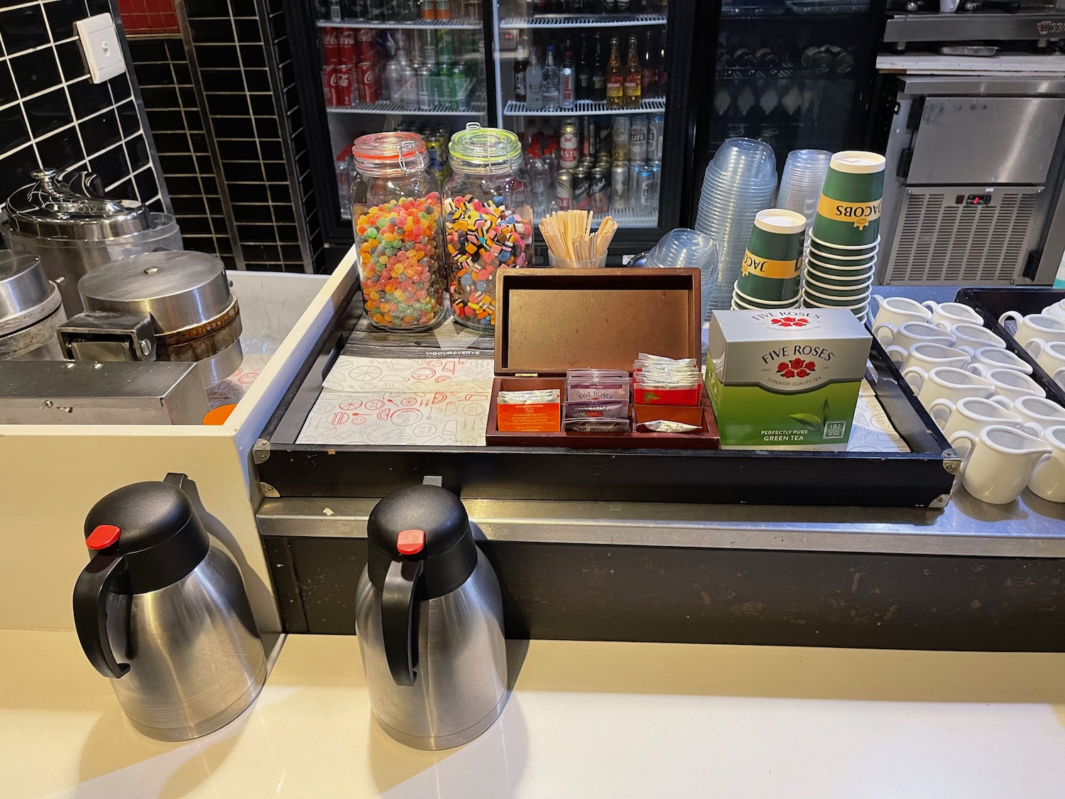 a counter with a variety of candy and coffee cups