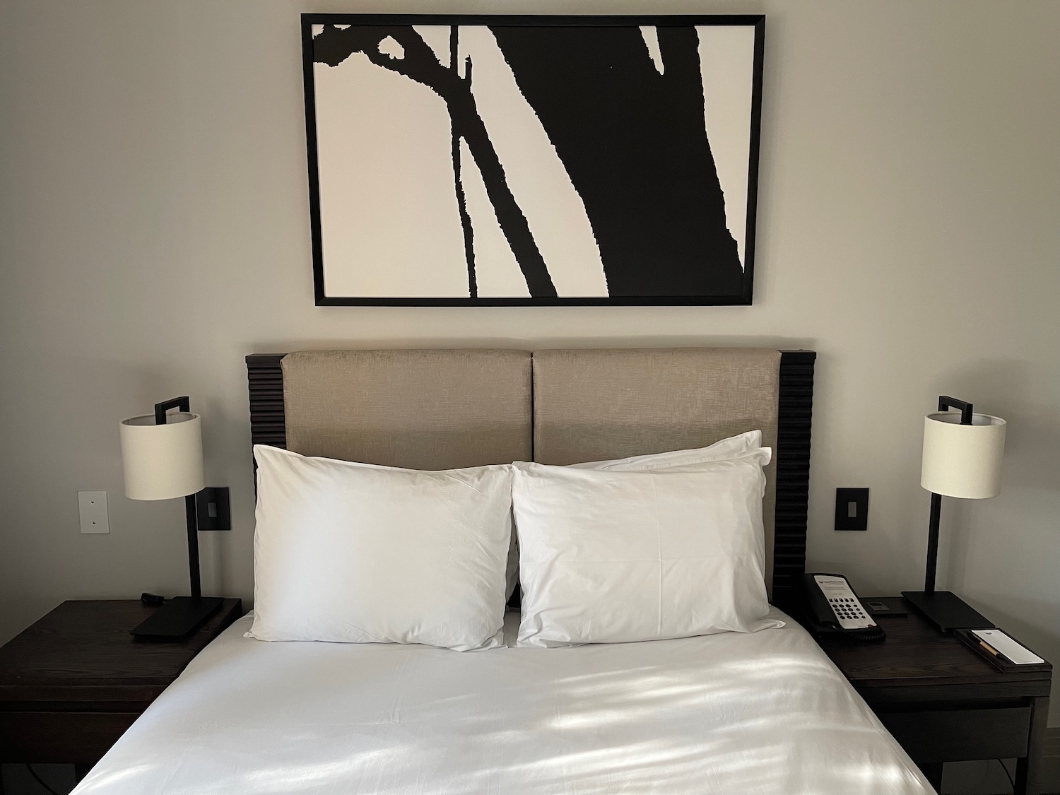 a bed with a white bedding and a black and white painting above it