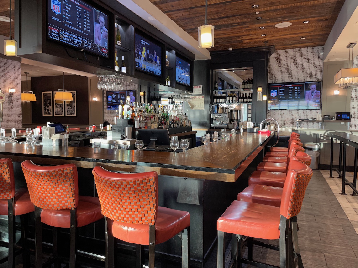 a bar with a row of chairs and a television screen