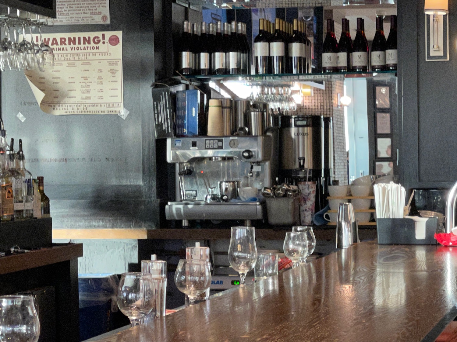 a bar with wine glasses and bottles on the counter