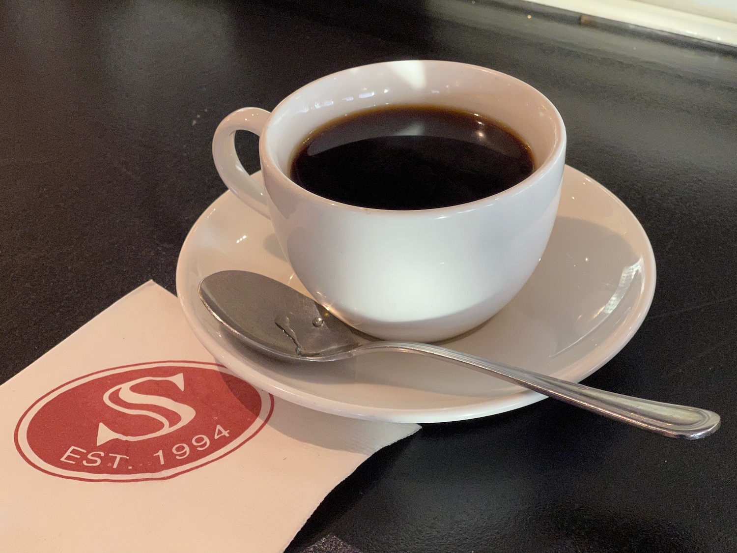 a cup of coffee on a saucer with a spoon