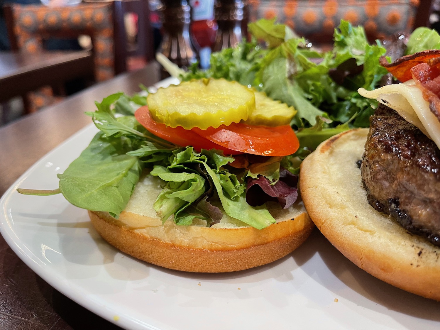 a burger with lettuce tomato and pickles on a plate