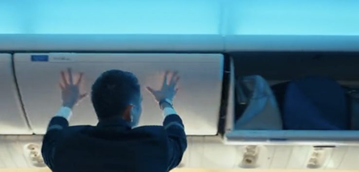 a man in a suit touching the ceiling of an airplane