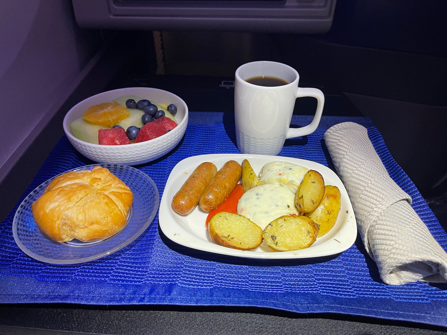 a plate of food and a cup of coffee on a blue place mat