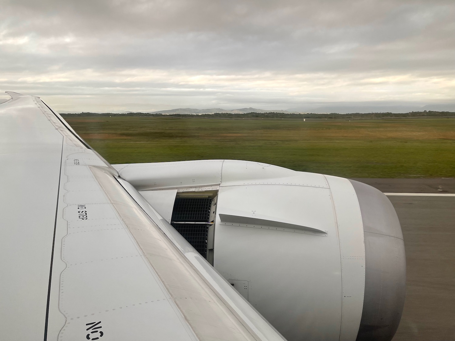 an airplane wing with grass and a field in the background