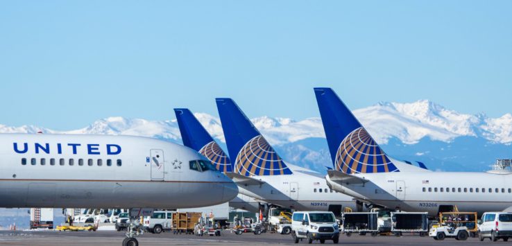 airplanes parked on a runway with mountains in the background