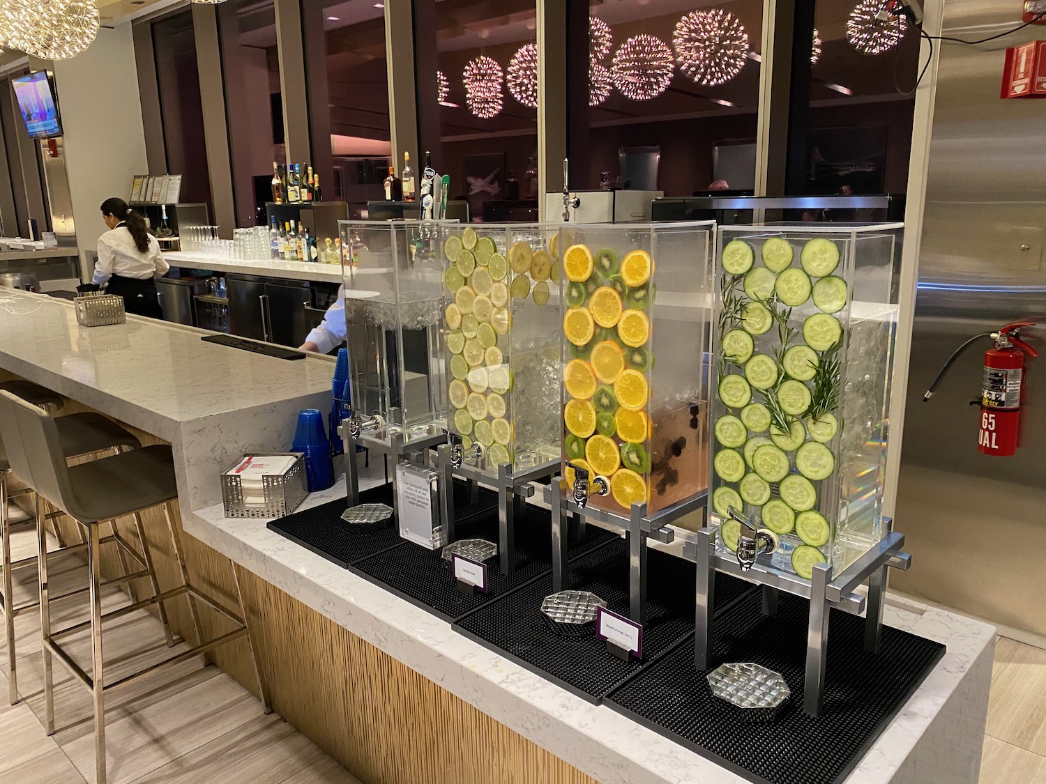 a row of water dispensers with slices of lemons and cucumbers