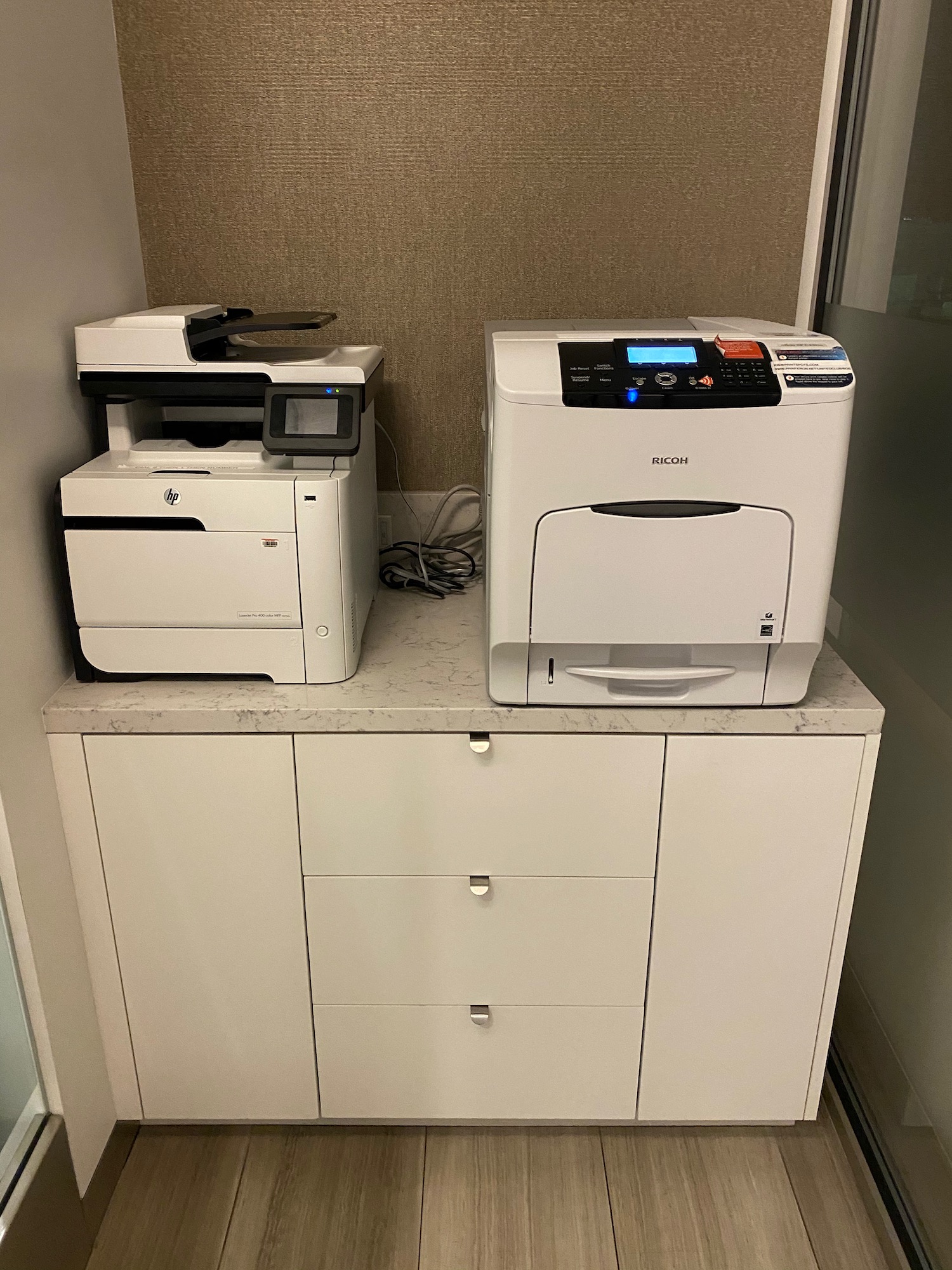 two white printer on a white cabinet