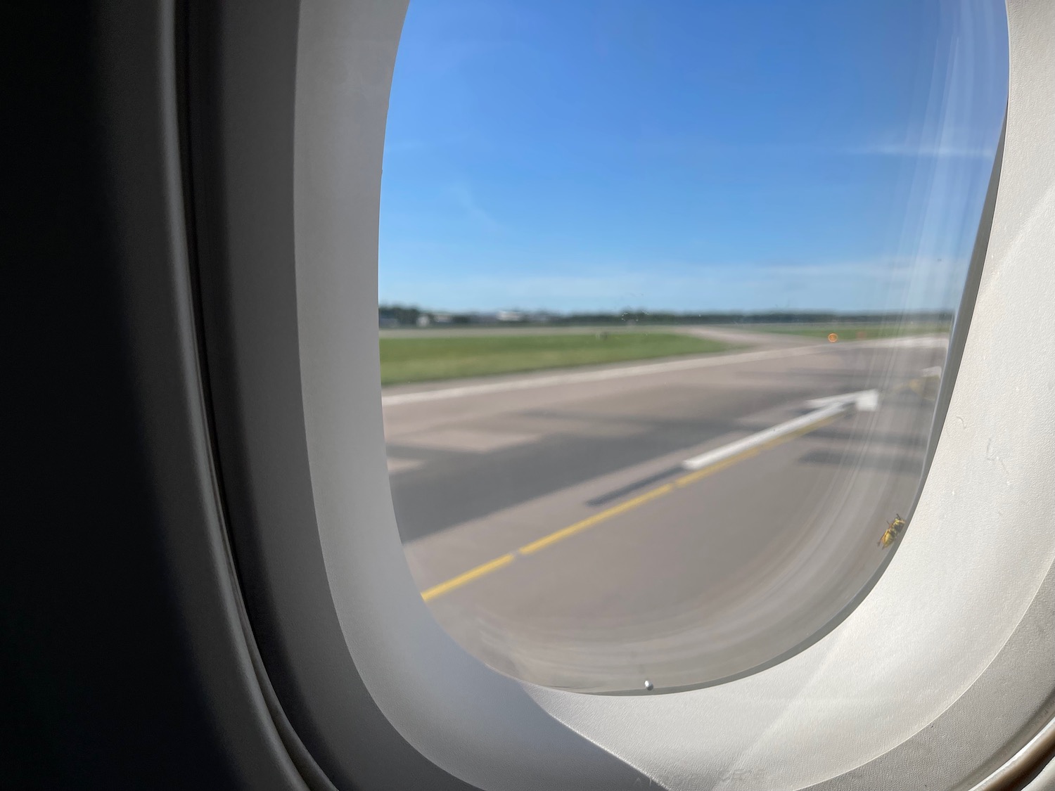 an airplane window with a runway and grass