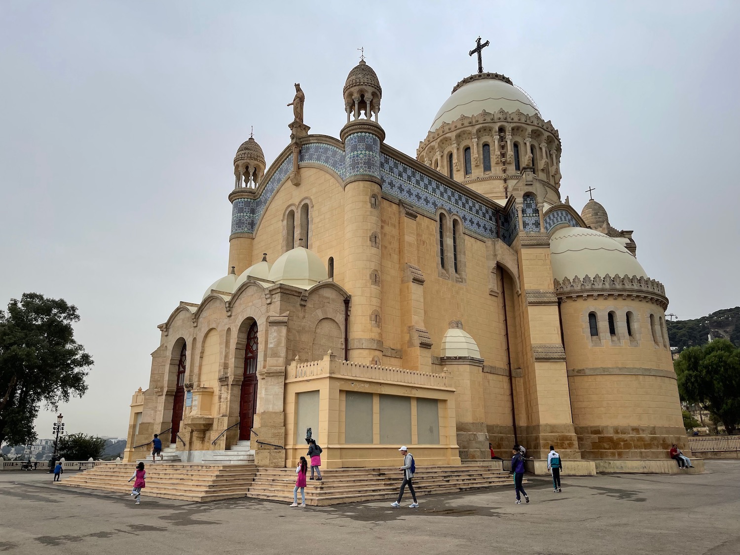 a large building with domes and crosses with Notre Dame d'Afrique in the background