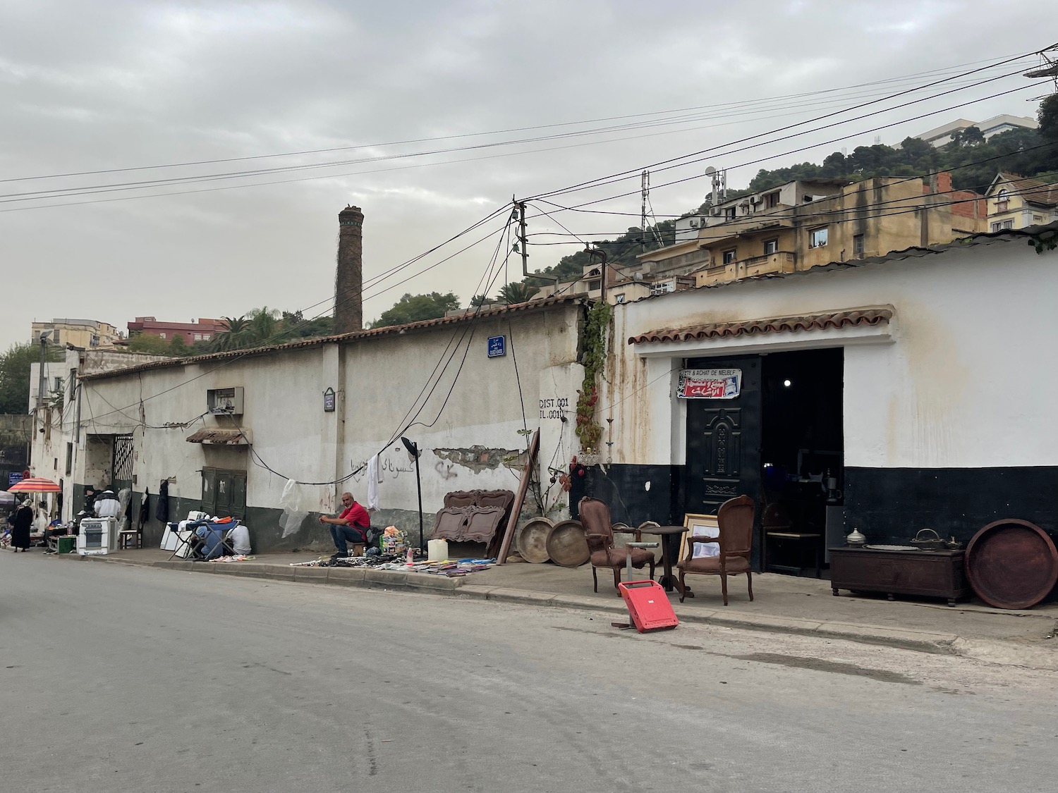 a street with a building and a man sitting on the side of the road