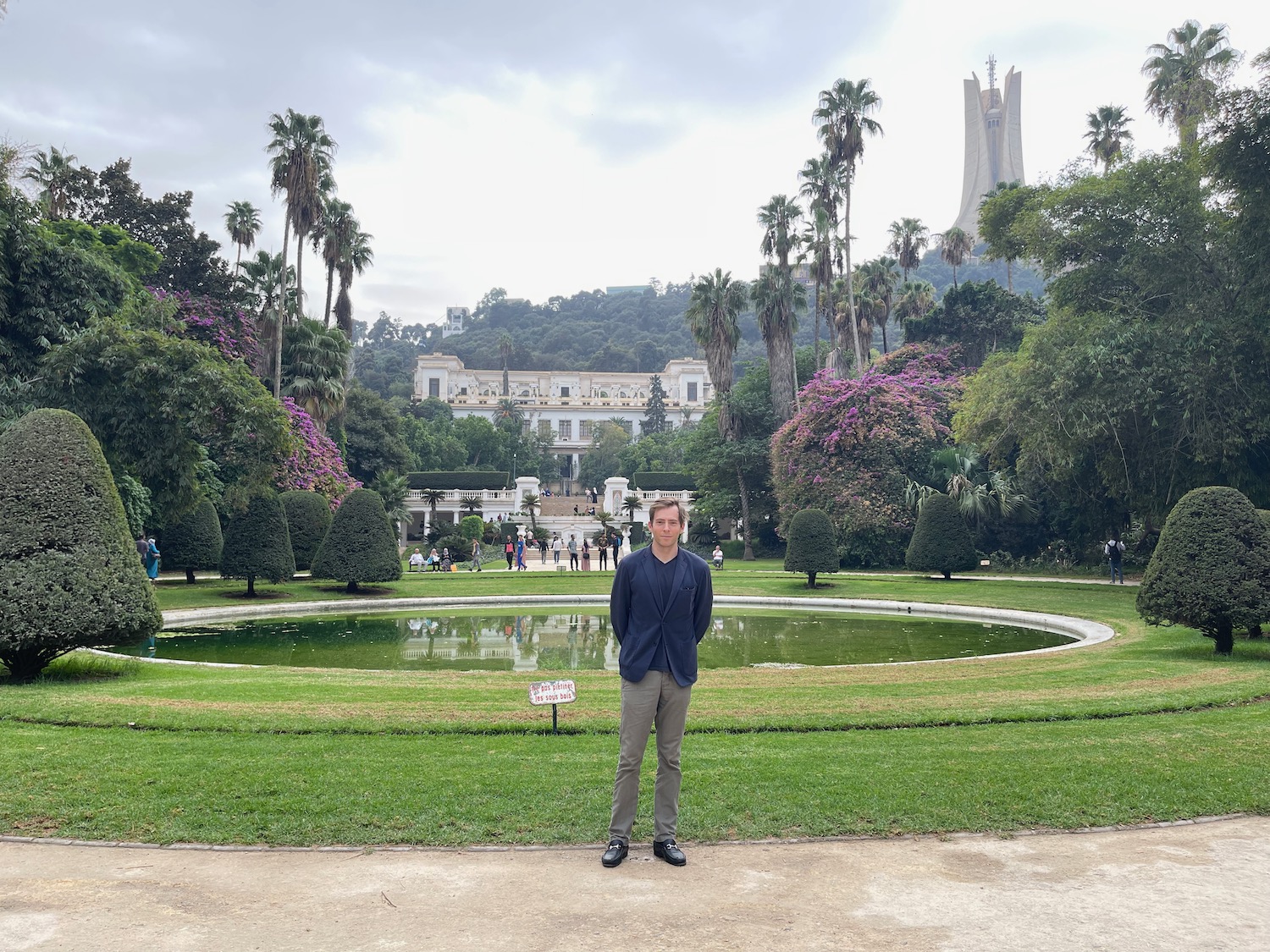 a man standing in front of a pond in a park