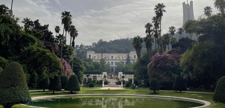 a large circular pool with trees and a building in the background