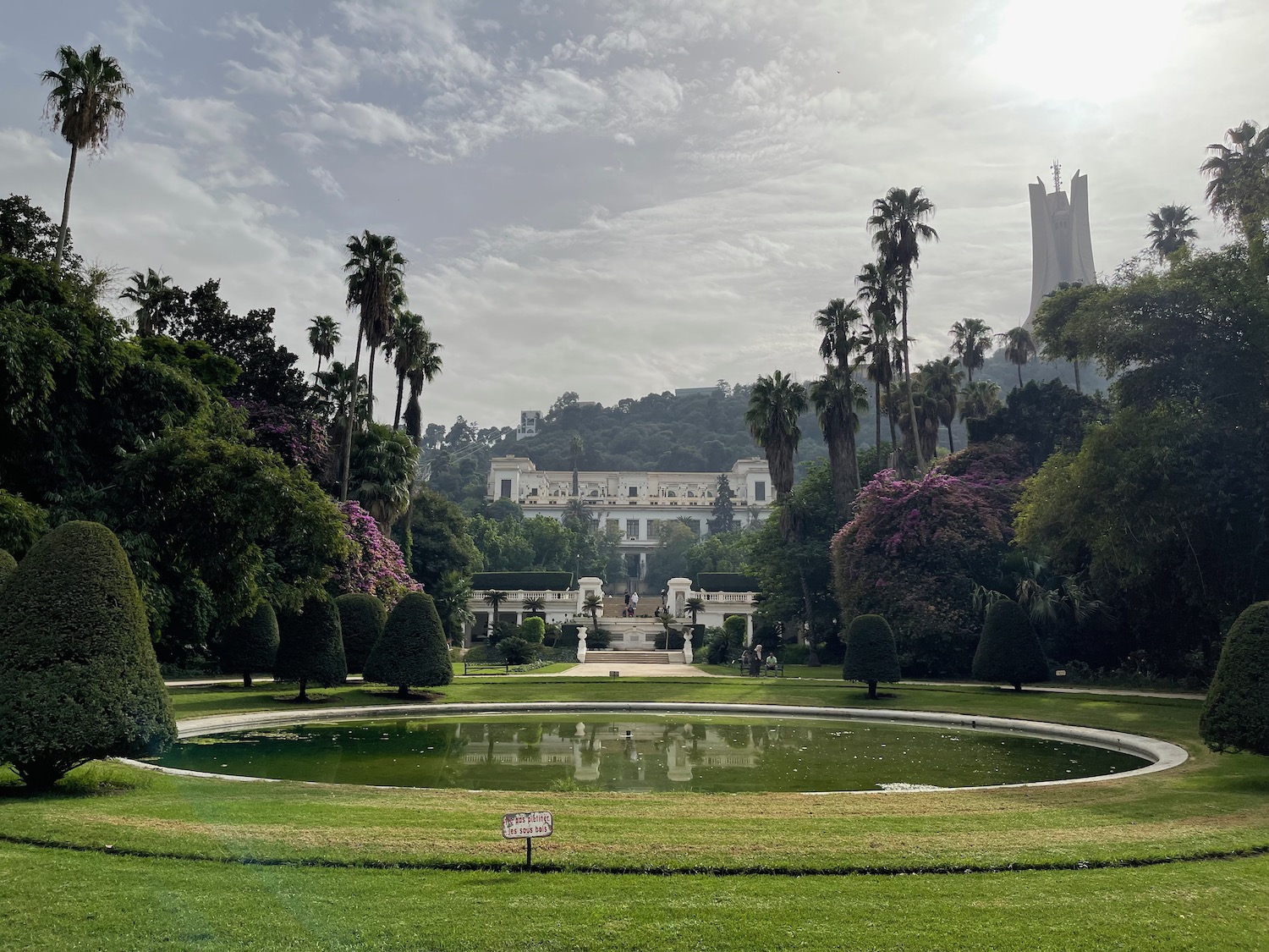 a large circular pool with trees and a building in the background