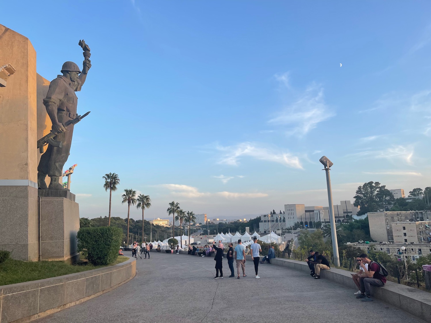 a group of people walking on a path with a statue of a man