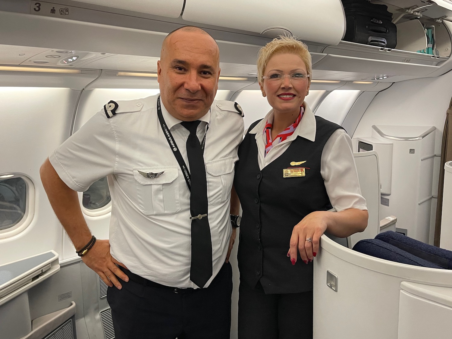 a man and woman in uniform standing in an airplane