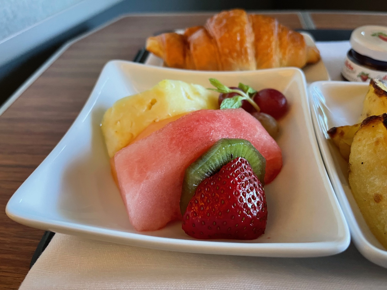 a plate of fruit and croissant