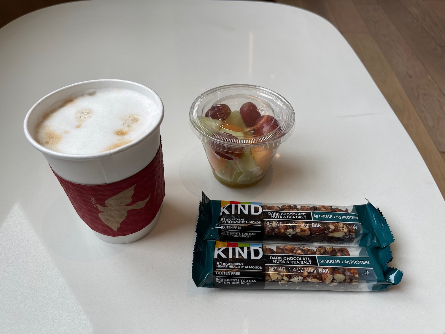 a cup of coffee and fruit and candy bars on a table