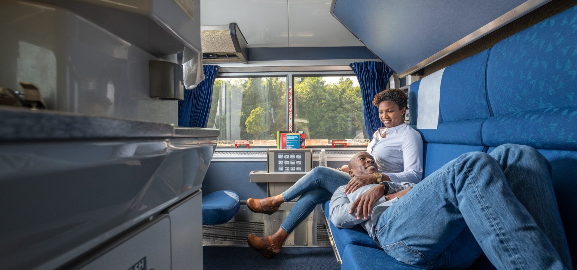 a man and woman sitting on a couch in a train